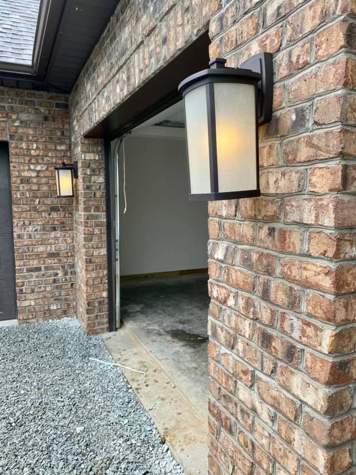 Brick building exterior with garage and two lit outdoor lights. 
