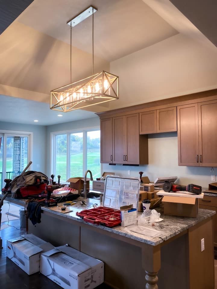 Kitchen with island, new light fixture, cabinets, and boxes, possibly under construction.