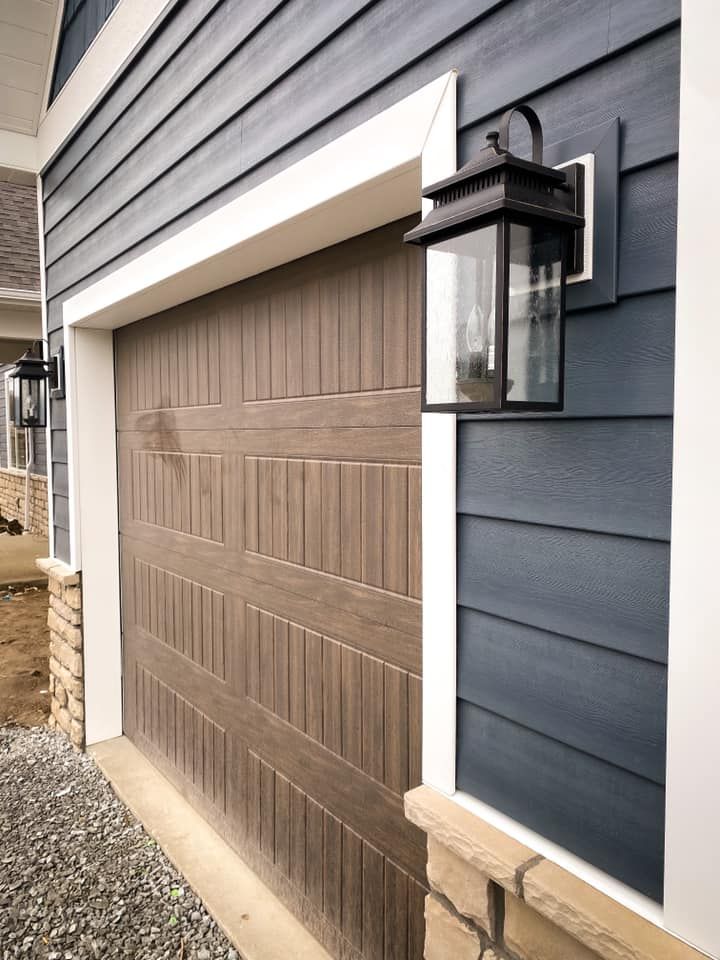 Garage door with brown panels, blue siding, and a black lantern.