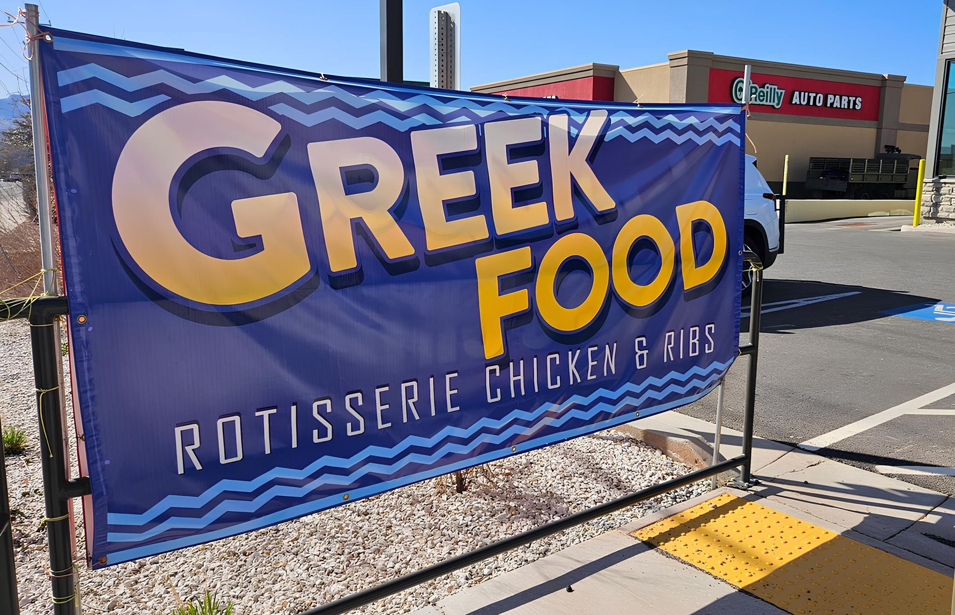 A sign for Greek food rotisserie chicken and ribs