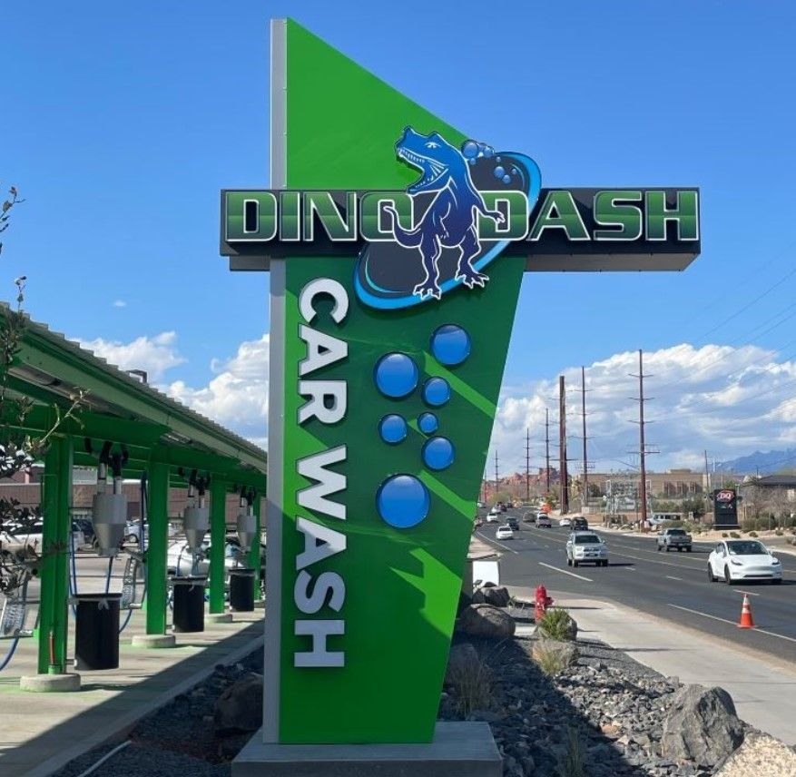 A green sign that says ding dash car wash.