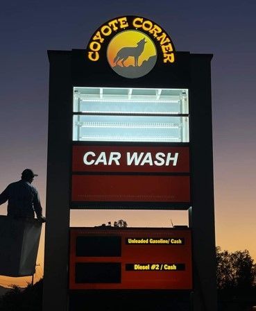 A coyote corner car wash sign is lit up at night.