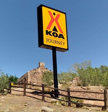 A koa journey sign in front of a fence.