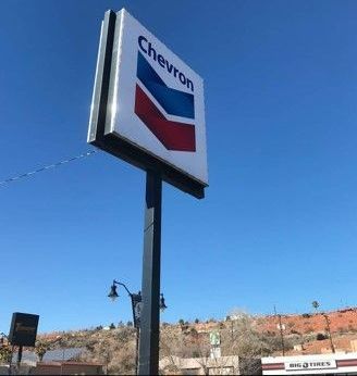 A chevron gas station sign is against a blue sky.