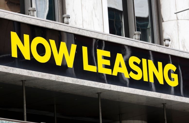 A sign on the side of a building that says now leasing.