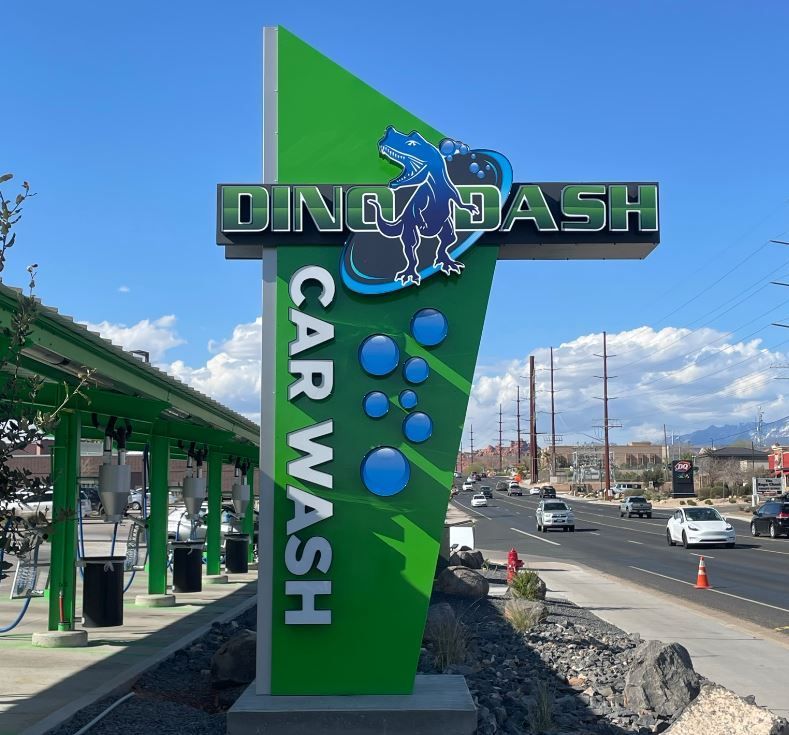 A green sign that says  'dino dash car wash' on it.