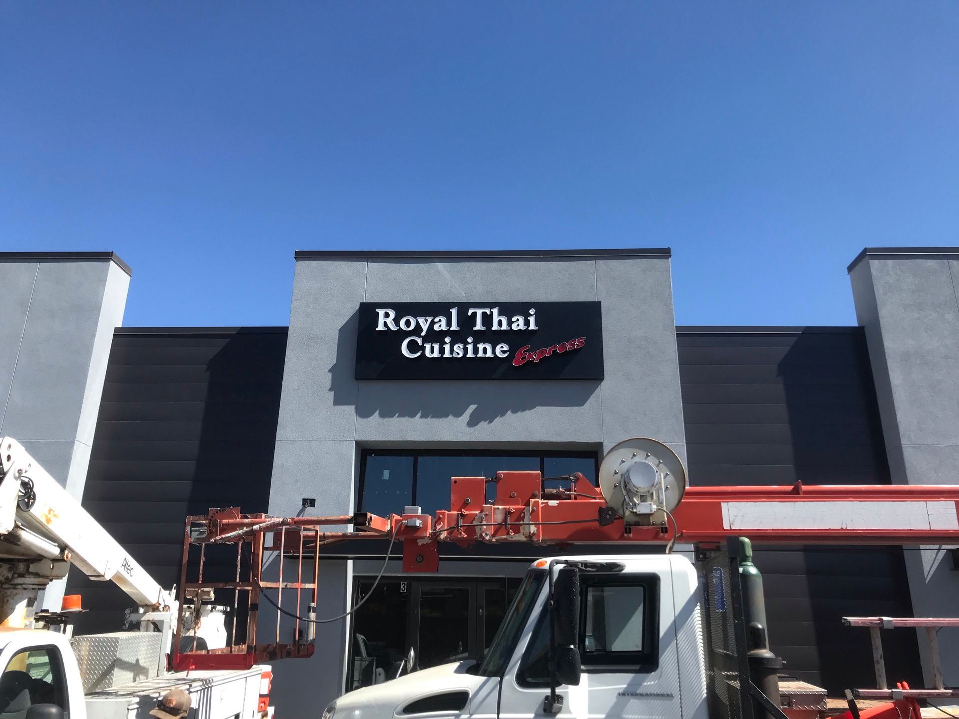 A truck is parked in front of a building that says royal thai cuisine.