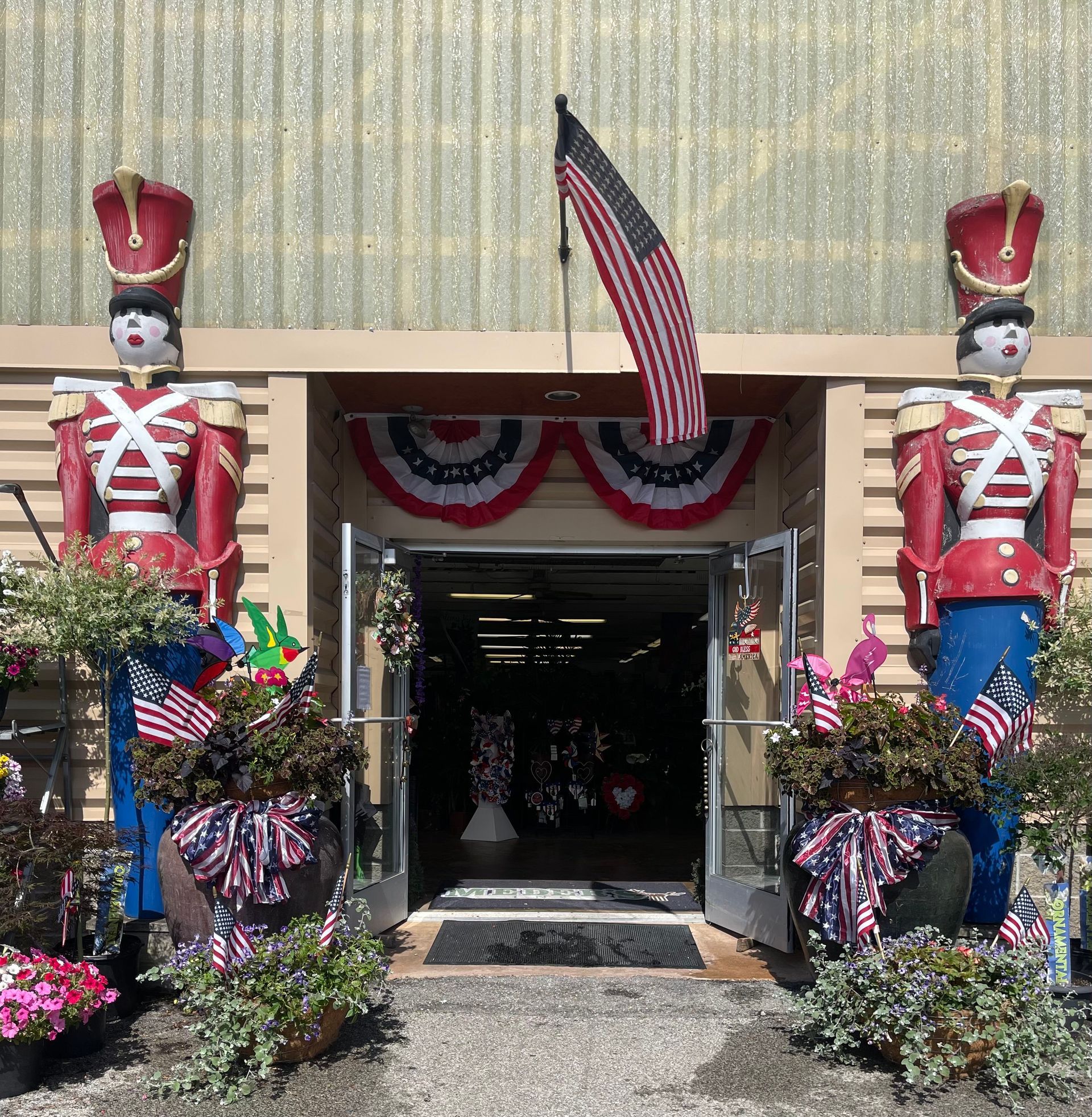 A store front with two toy soldiers statue and an American flag