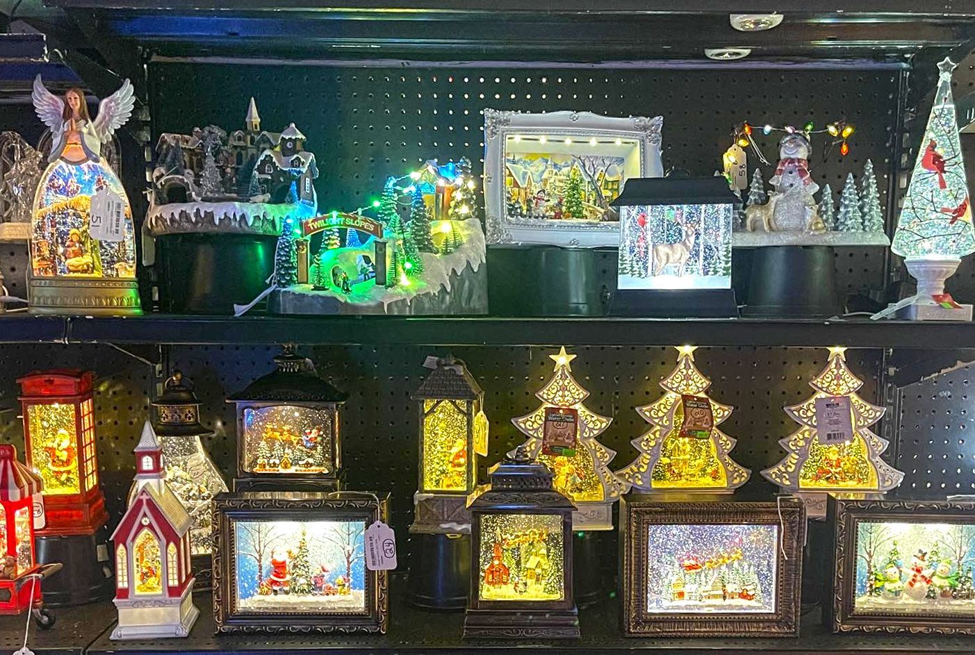 A shelf filled with lots of christmas decorations including lanterns and trees.