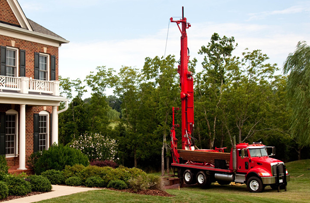 A water drilling truck in front of a house