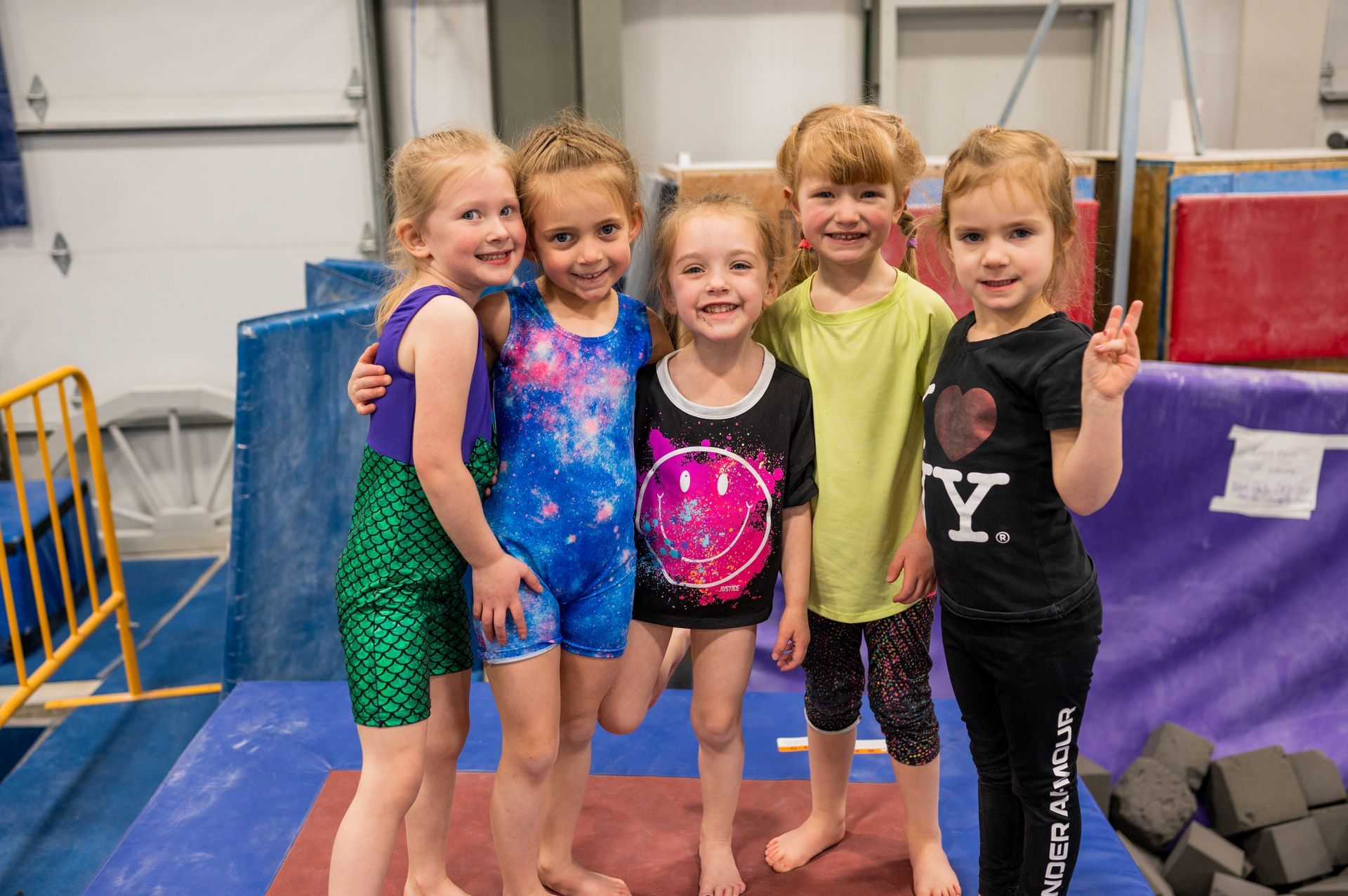 A group of young girls are posing for a picture in a gym.