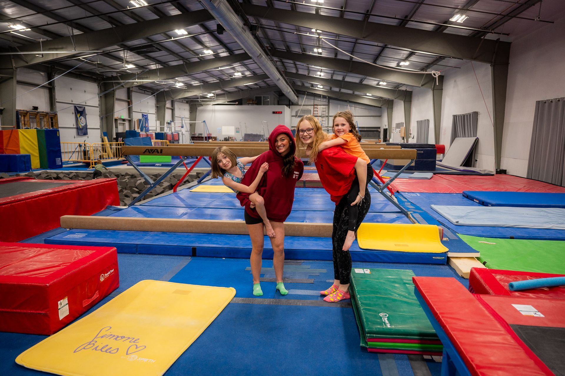 A group of people are standing on a balance beam in a gym.