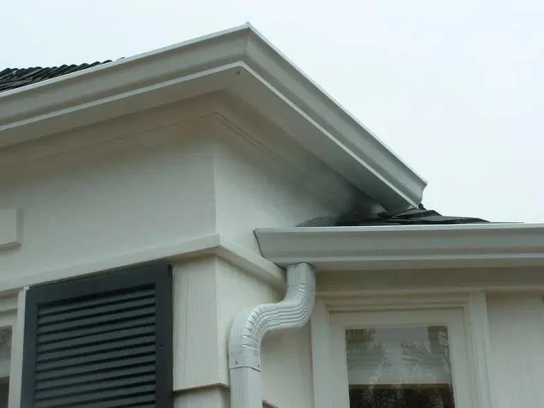 A white house with black shutters and a white gutter