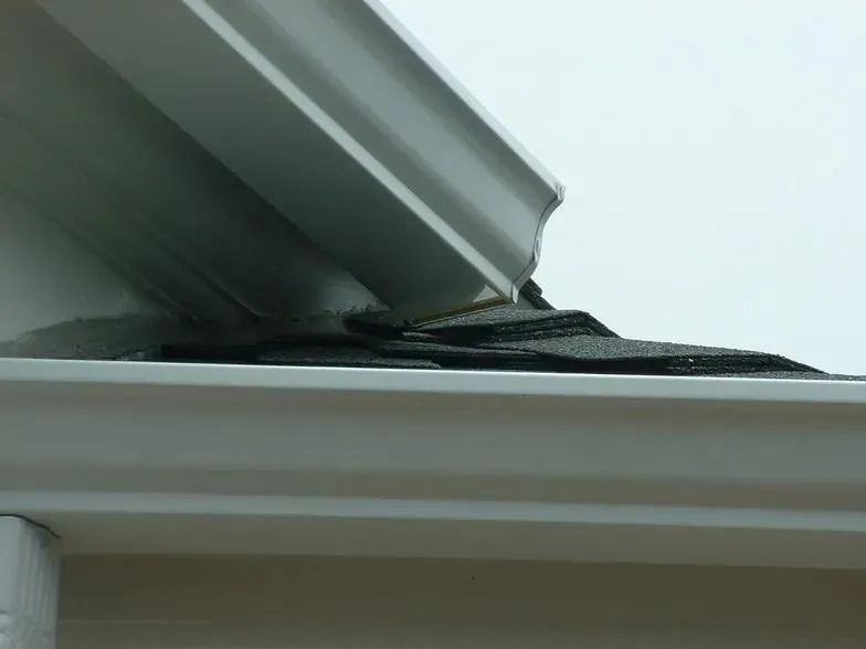 A close up of a gutter with a roof in the background