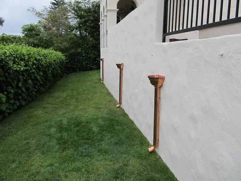 A white wall with copper pipes attached to it