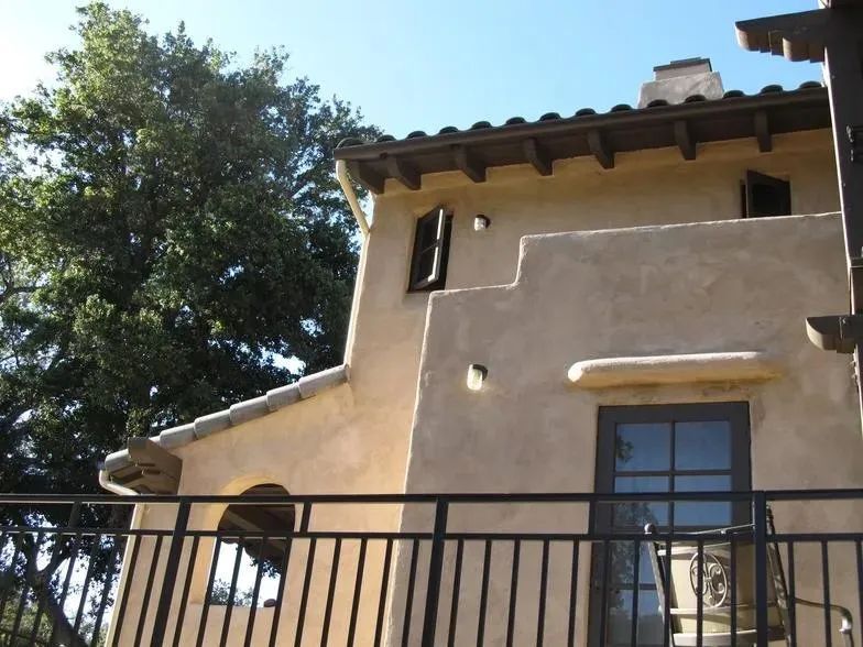 A house with a balcony and a tree in the background