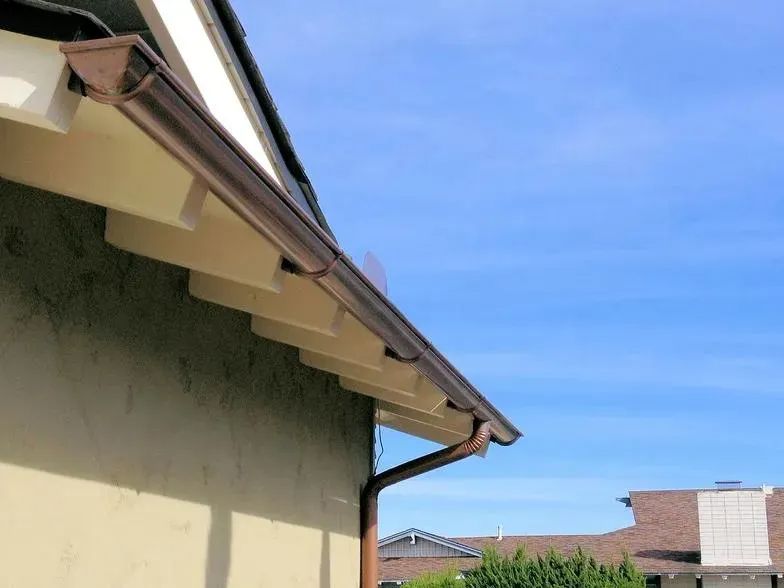 A gutter on the side of a house with a blue sky in the background