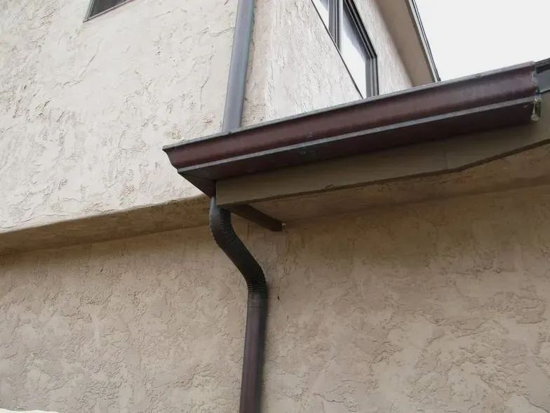 A brown gutter is attached to the side of a building