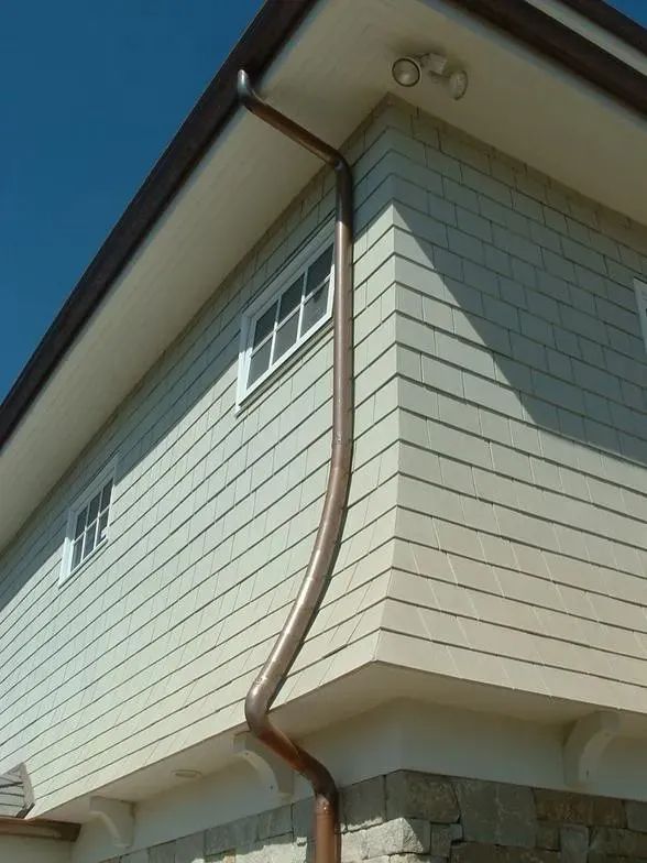A white house with a copper gutter on the side