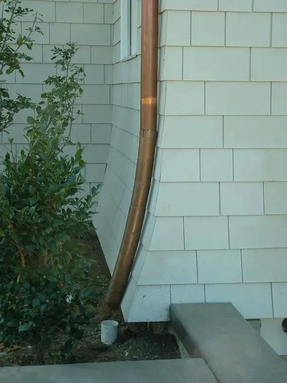 A white brick building with a copper pipe on the side