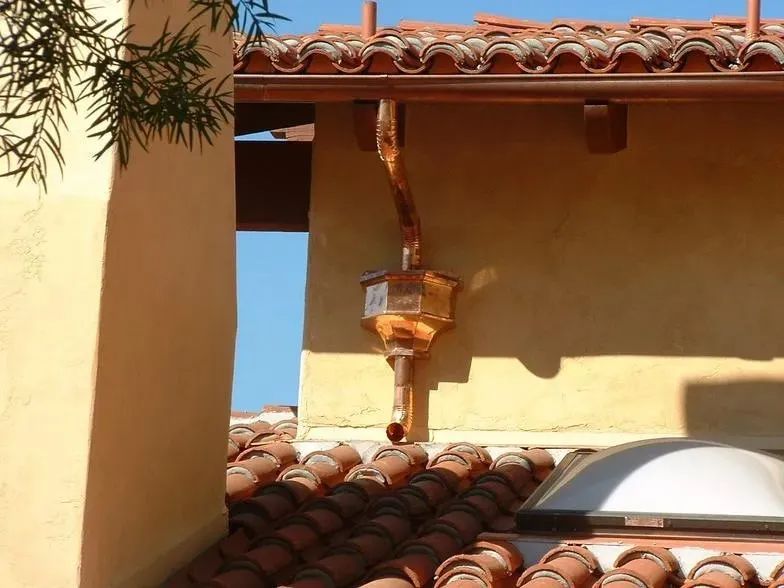 A copper gutter is hanging from the side of a building