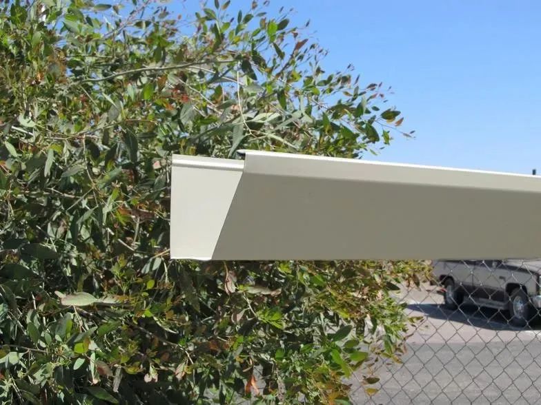A white gutter is sitting next to a tree.