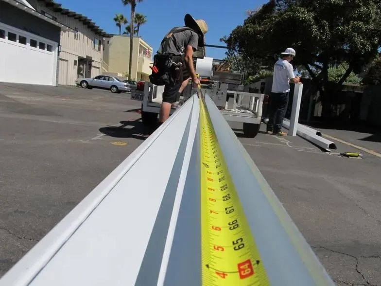 A man is measuring a piece of metal with a tape measure