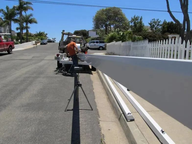 A man is standing next to a white railing on the side of the road