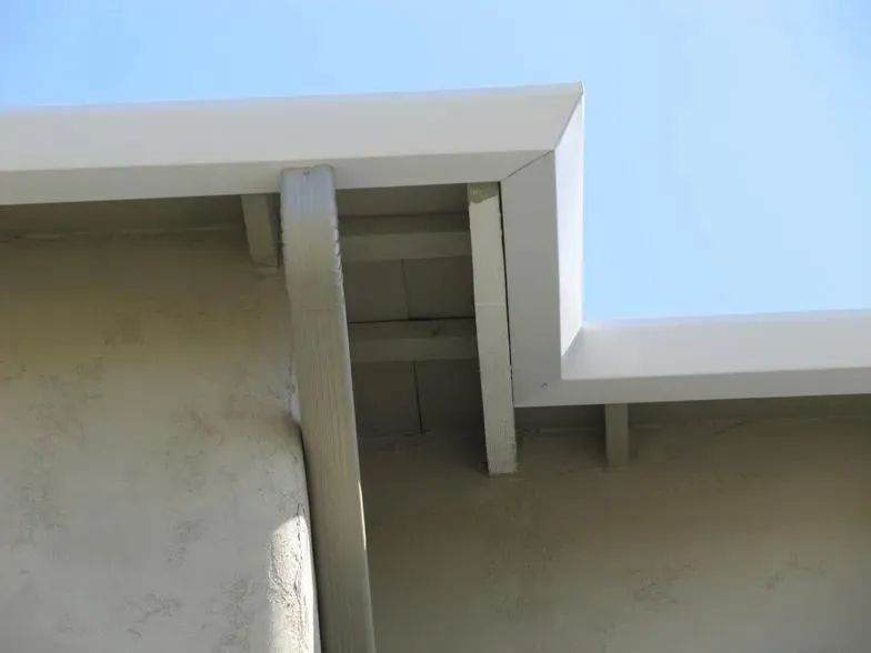 A close up of a white roof with a blue sky in the background.