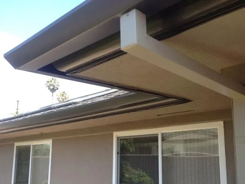 The roof of a house with a gutter and a window.
