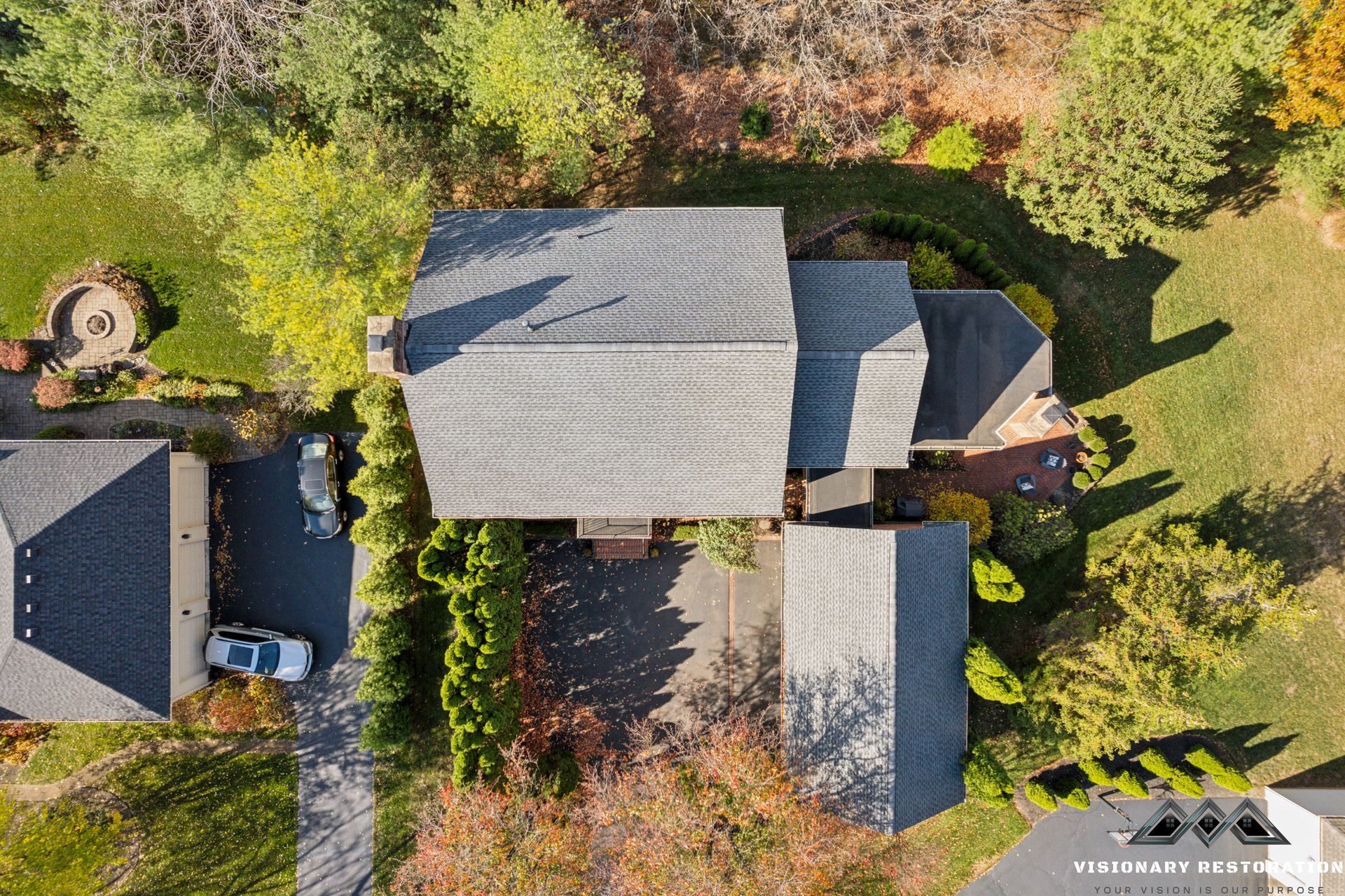 Overhead view of a house with a gray roof, surrounded by trees and a driveway.