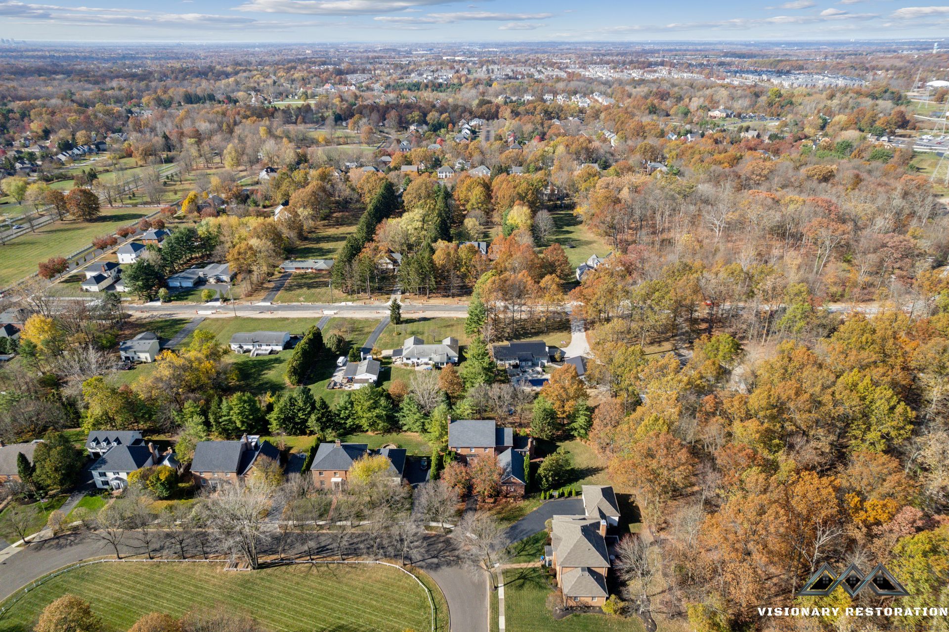Aerial view of suburban homes surrounded by trees with autumn foliage.