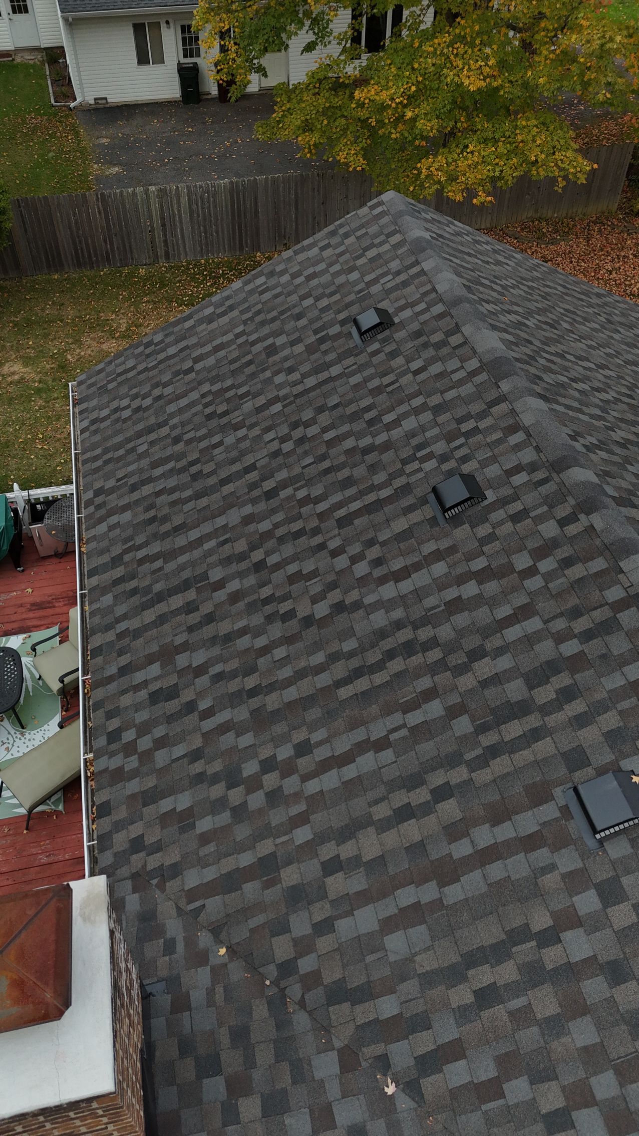 Dark gray asphalt shingle roof, three vents, viewed from above, surrounded by trees.