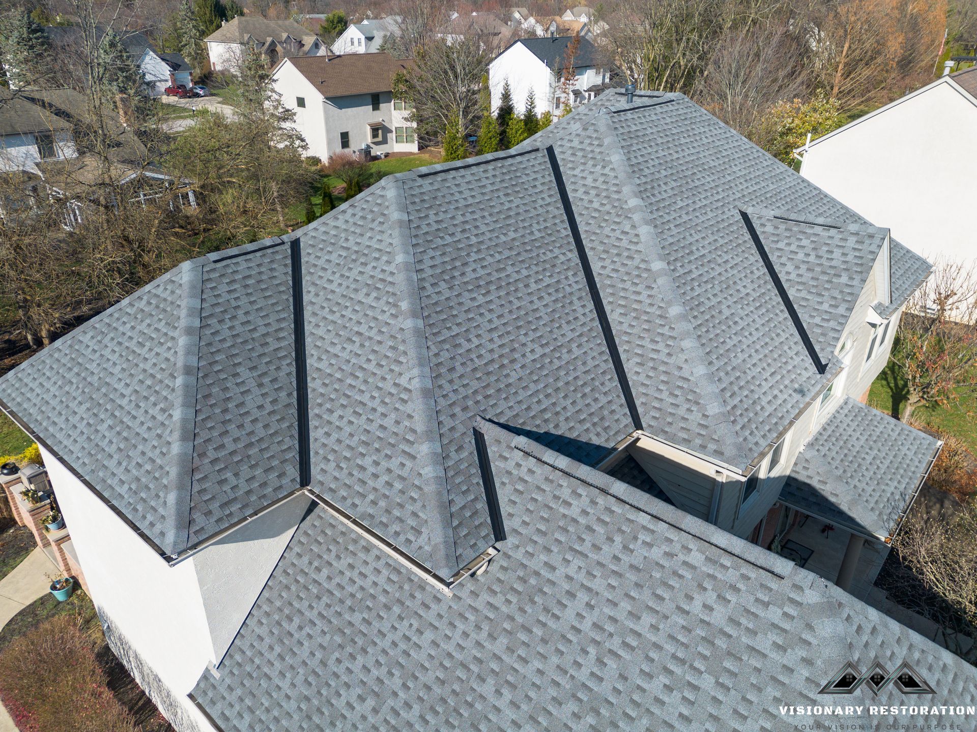 Gray asphalt shingle roof on a multi-gabled house in a suburban setting.