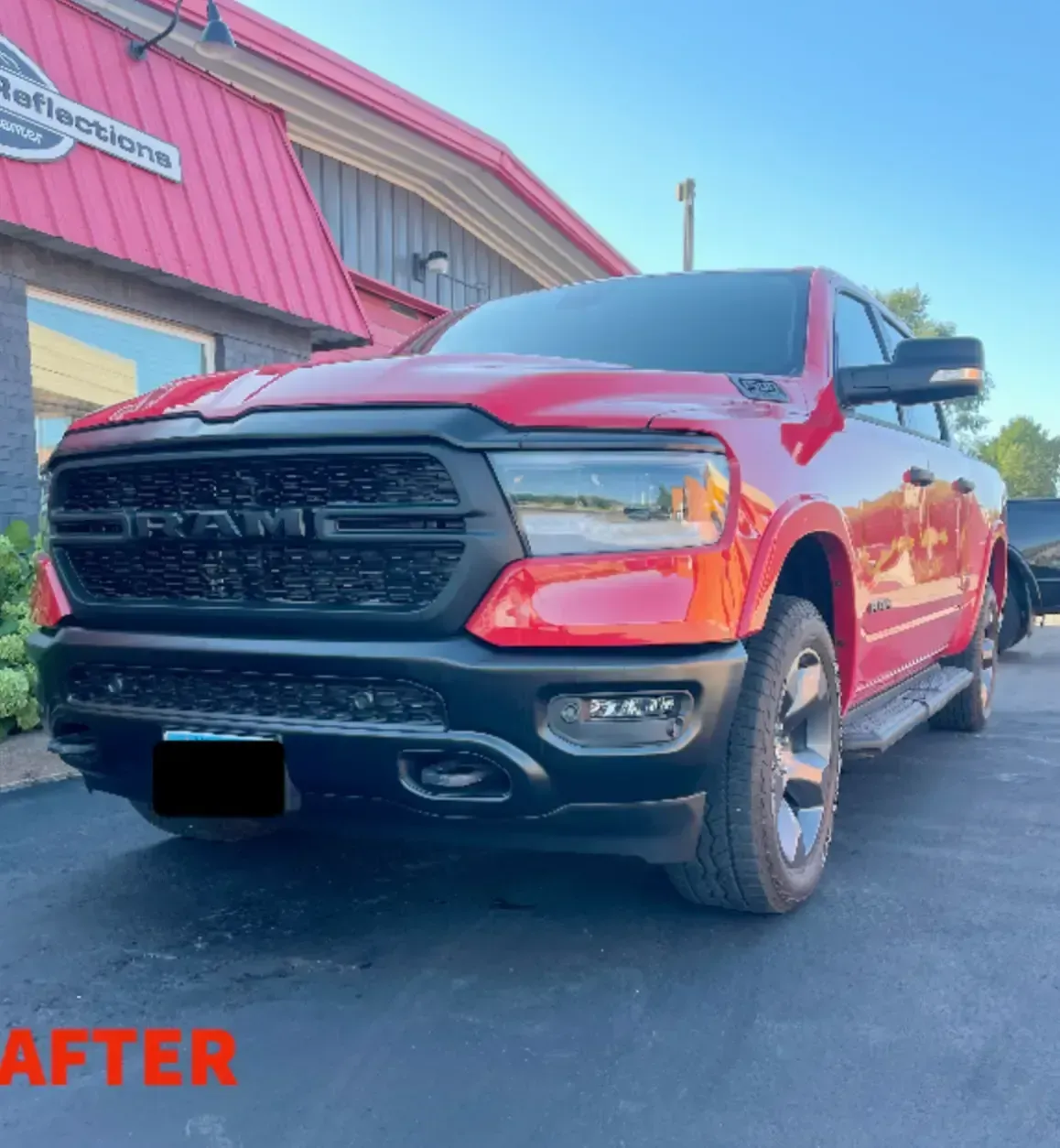 A red Ram pickup truck with a black grille and bumper parked in front of a building with a red roof.