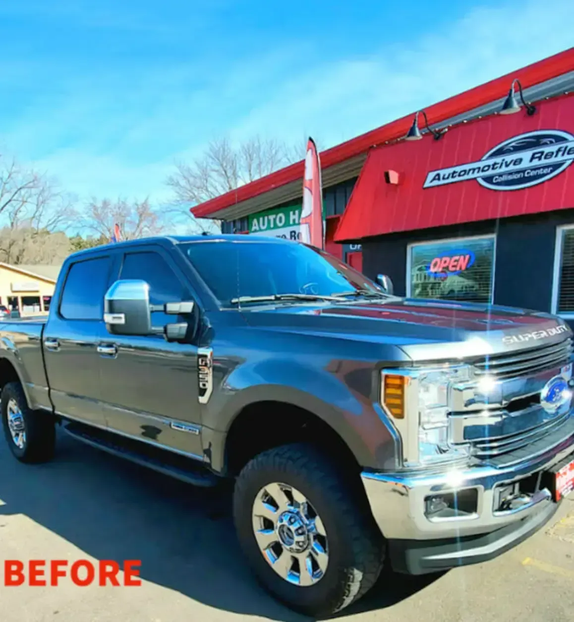 A gray Ford Super Duty truck parked outside an automotive repair shop on a sunny day, labeled as a 