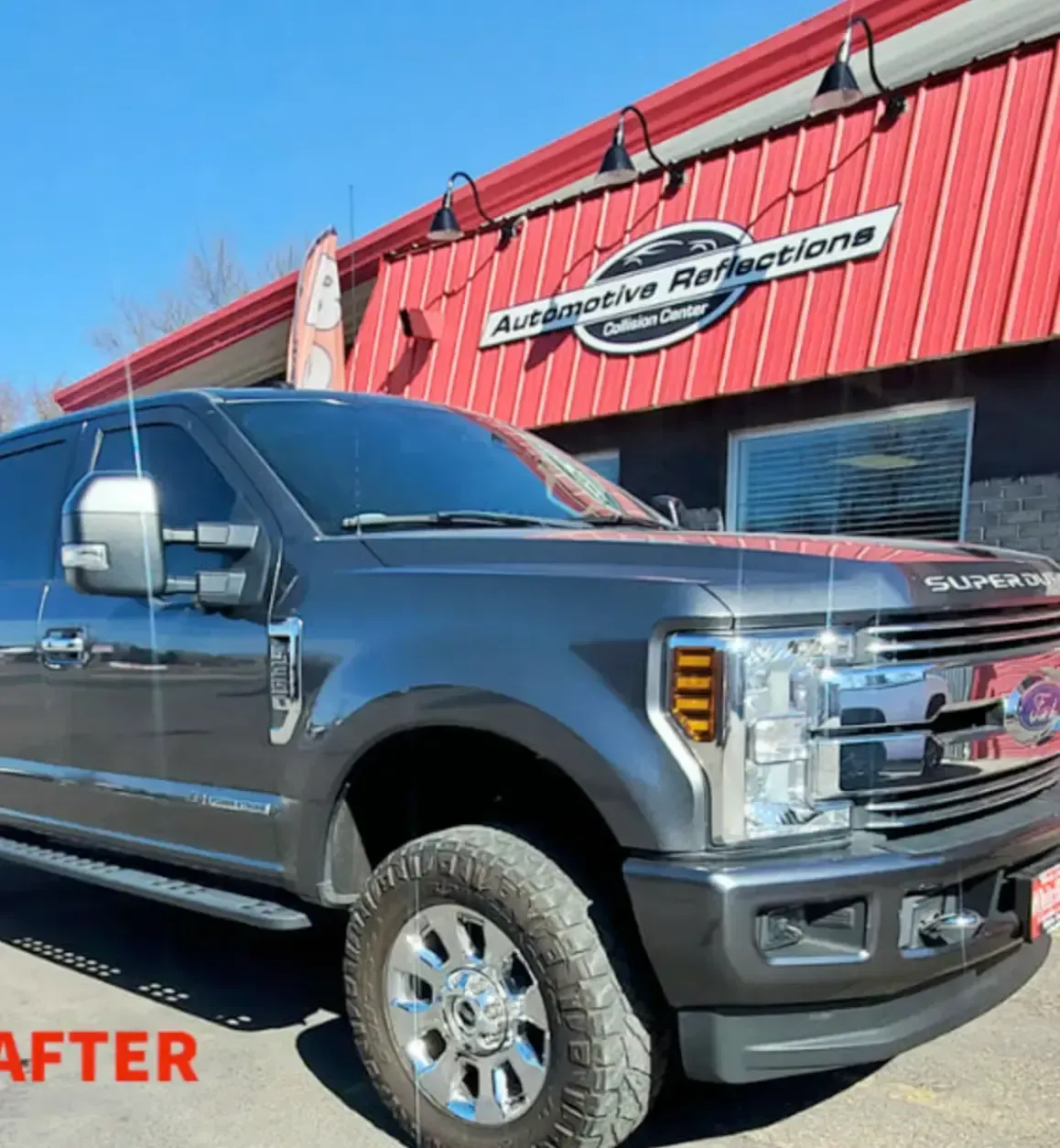 A dark gray Ford Super Duty pickup truck parked in front of an Automotive Reflections shop under a bright blue sky.