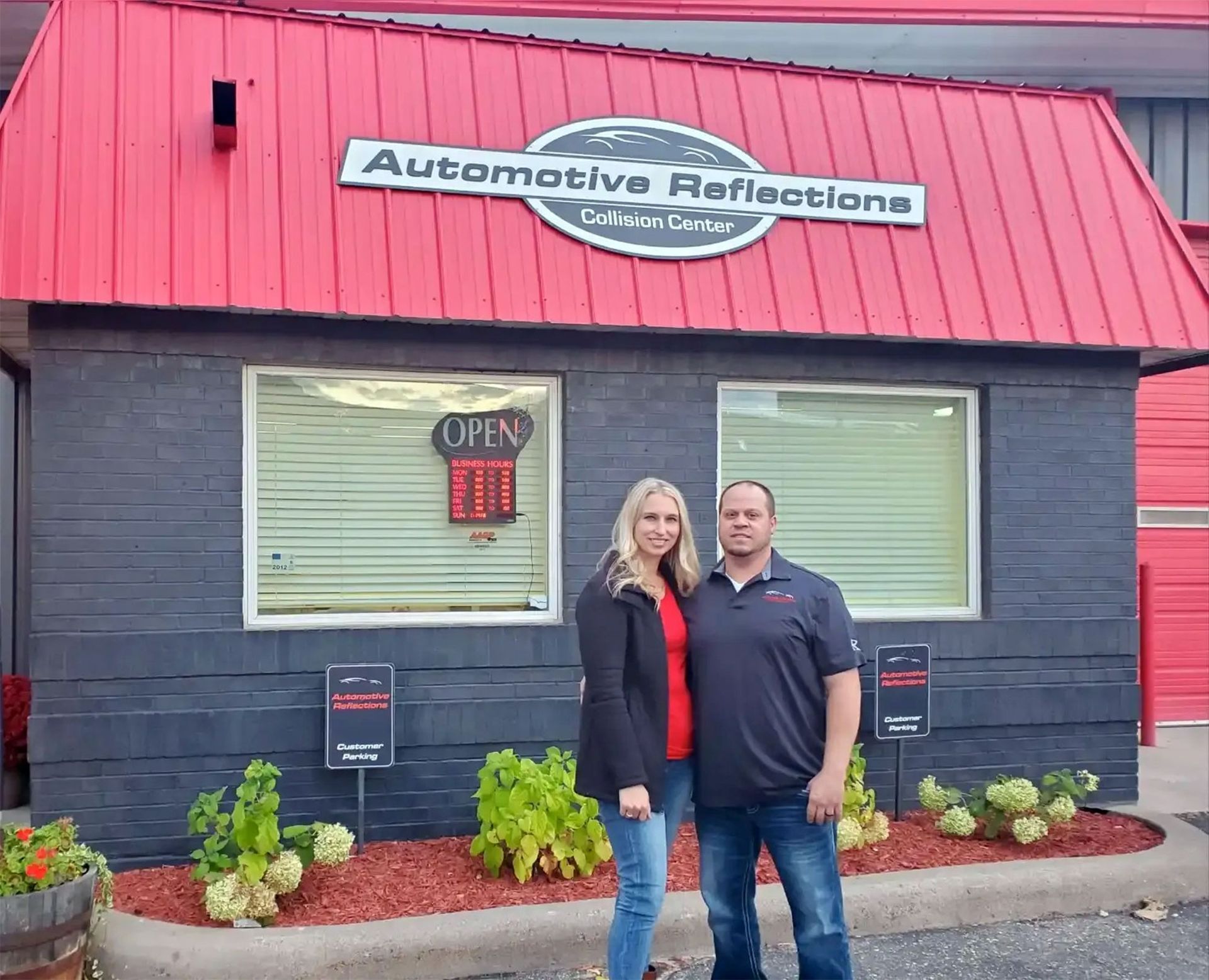 A couple stands in front of the brick exterior of 