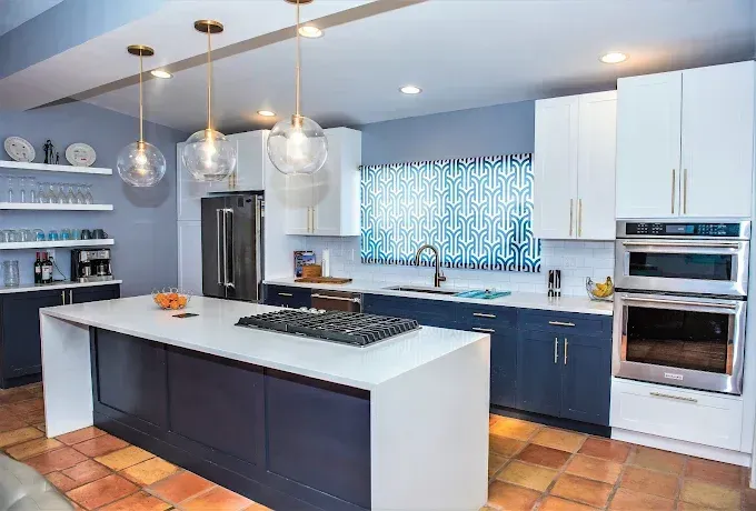 Modern kitchen with blue and white cabinets, island, and pendant lights.