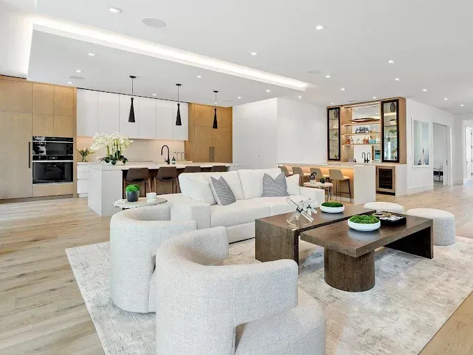 Modern open-concept living space with white furniture, a kitchen, and a bar area.