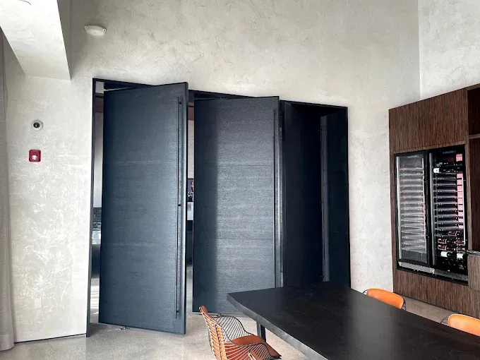 Three dark doors in a modern room, a dark table, and a built-in wine fridge.