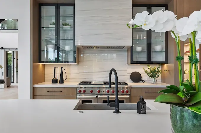 Modern kitchen with white countertops, stainless steel appliances, and black accents.