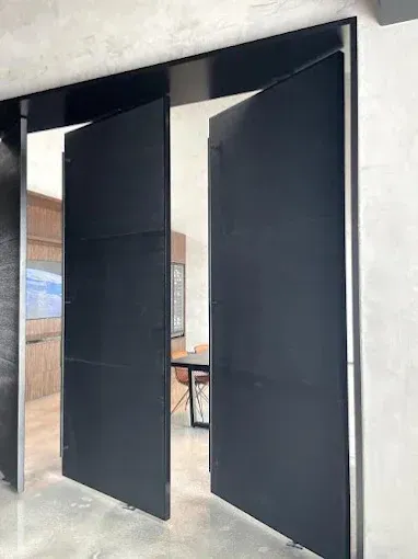 Black metal double doors open to reveal an office space.