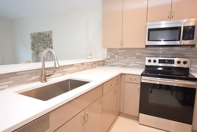 Modern kitchen with light cabinets, stainless steel appliances, and white countertops.