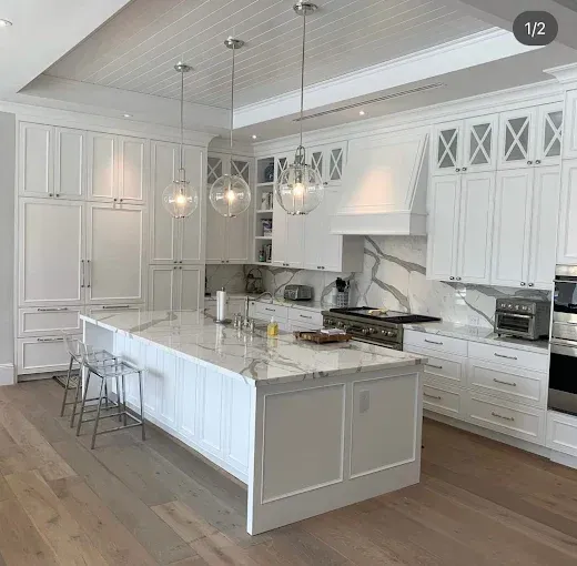 White kitchen with island, cabinets, stainless steel appliances, and light wood floors.