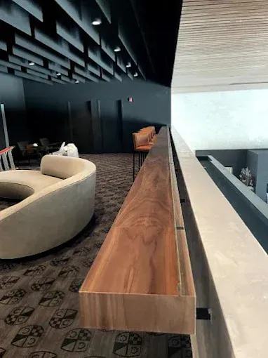 Balcony with a wooden ledge, gray carpet, and seating areas.