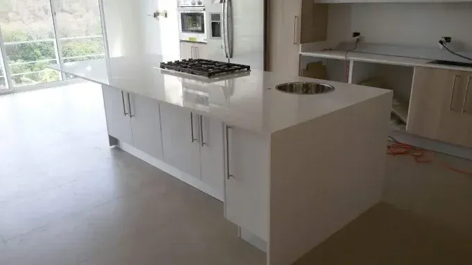 White kitchen island with stovetop, cabinets, and sink; in a modern kitchen.