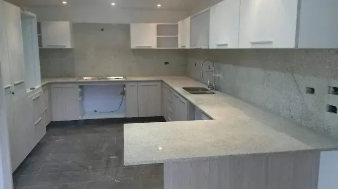 U-shaped kitchen with light gray cabinets, white upper cabinets, light countertops, and gray flooring.