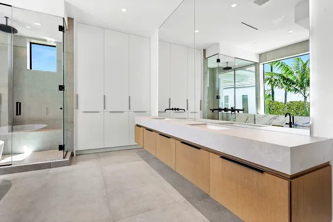 Modern bathroom with glass shower, long vanity, and tall white cabinets.