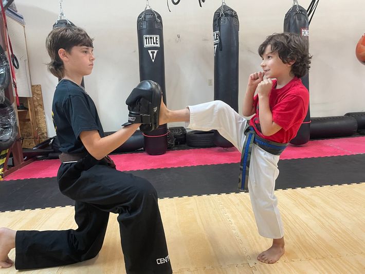 Two young boys are practicing karate in a gym.